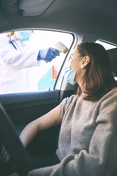 Nie chciałabyś raczej wiedzieć. zamaskowana młoda kobieta badana przez lekarza podczas siedzenia w samochodzie - Zdjęcie, obraz