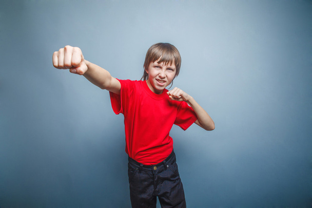 Muchacho, adolescente, doce años de rojo en camisa, rojo mostrando fis
 - Foto, Imagen
