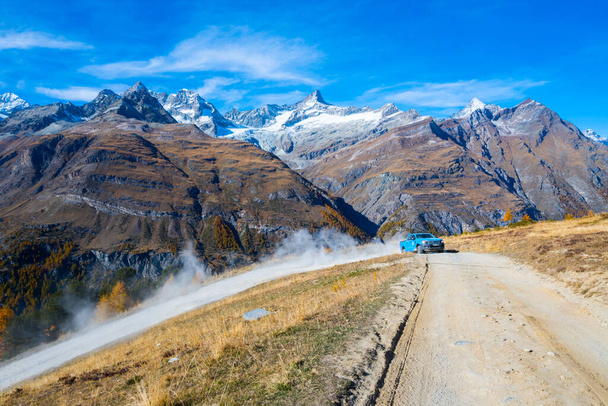 Autot kulkevat mäkeä ylös tiellä Sveitsin Alpeilla taustalla.Zermatt Sveitsi. - Valokuva, kuva