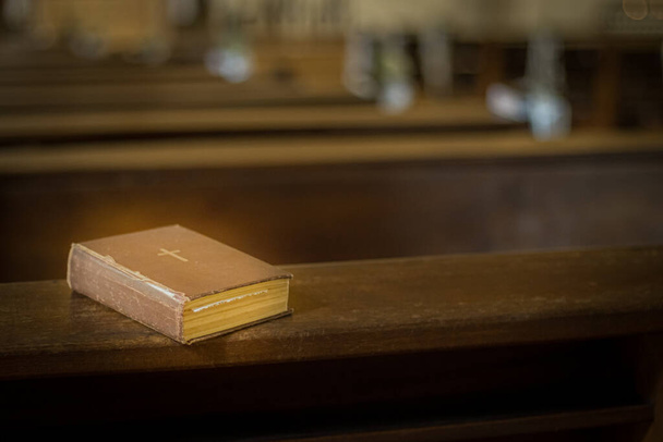 教会のベンチで聖書。一冊の小さな本で神の言葉。ソフト選択的フォーカス。写真のための人工的に作成された穀物 - 写真・画像