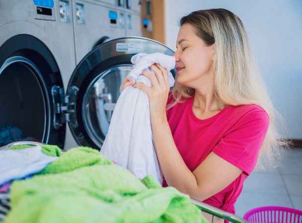Young beautiful woman washes and dries clothes in the laundry. - Fotoğraf, Görsel