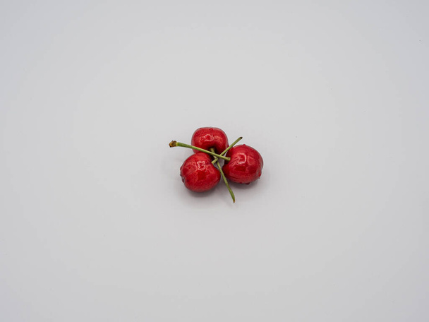 Tres cerezas rojas jugosas, dulces, orgánicas que brillan con tentadoras gotas de agua. - Foto, Imagen