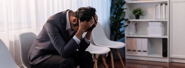 Nervous and panic job applicant with stressful emotion on job interview while he sitting and waiting for his turn. Sad businessman holding his head with hands after making mistake. Trailblazing - Photo, Image