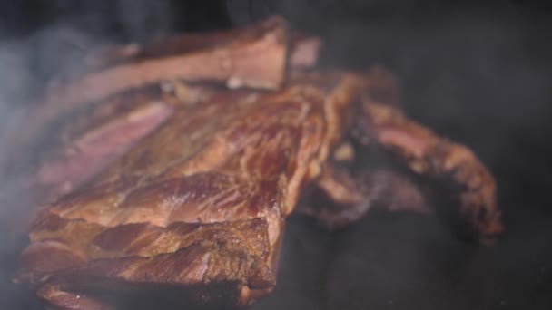 Frisch getrocknete Schweinerippchen auf schwarzem Hintergrund. Das Fleischprodukt ist hausgemacht. Fleisch auf Knochen. Frisch gegrilltes Schweinefleisch, trocken gereifter Grill. Weiche selektive Fokussierung - Filmmaterial, Video