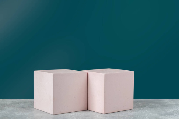  Два цементных кубических подиума на темном бирюзовом фоне. Макет для демонстрации косметической продукции. Копирование пространства - Фото, изображение