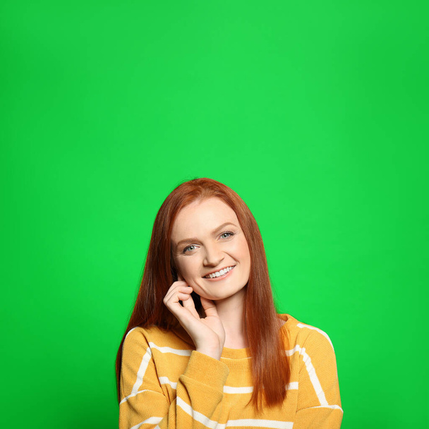 Chroma key compositing. Happy young woman with red hair against green screen - Foto, imagen