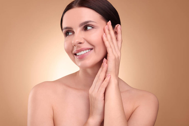 Beautiful woman with healthy skin on light brown background. Body Care - 写真・画像