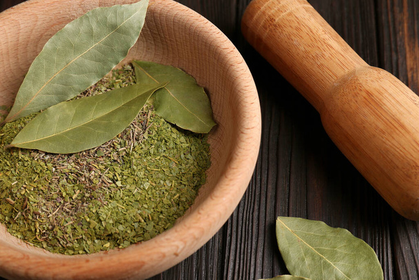 Mortar, pestle with whole and ground aromatic bay leaves in wooden bowl, closeup - Fotoğraf, Görsel
