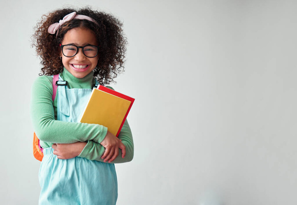 Škola, portrét dětského studenta s knihami pro znalosti, vzdělání a studium ve studiu. Happy, úsměv a mladá chytrá dívka dítě s brýlemi pro čtení na bílém pozadí s makupem prostoru - Fotografie, Obrázek