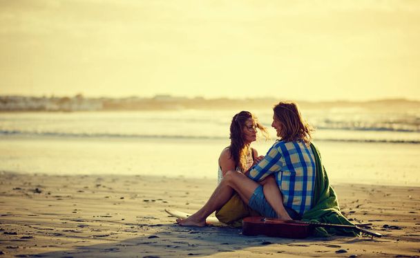 Me pierdo en tus ojos. una pareja sentada en la playa con las piernas entrelazadas - Foto, Imagen