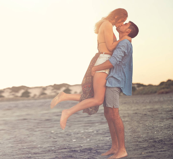Besos de verano. una pareja joven y cariñosa en la playa - Foto, imagen