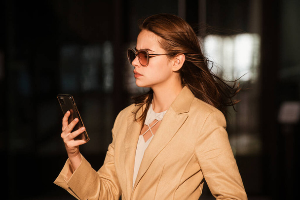 Street style photo of elegant fashionable business woman wearing trendy clothes talking on phone outdoor. Businesswoman with phone on street, business style. Business woman using phone - Foto, Imagem