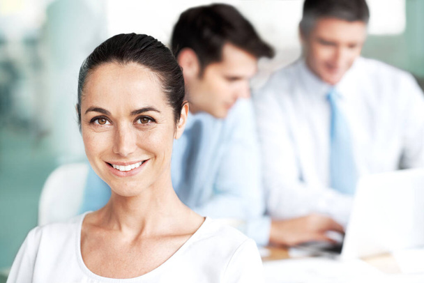 Confidence in her role on the team. Smiling young businesswoman sitting in a group meeting - Foto, imagen
