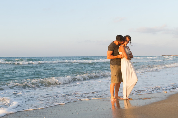 Jovem casal gosta de caminhar em uma praia nebulosa ao entardecer
. - Foto, Imagem