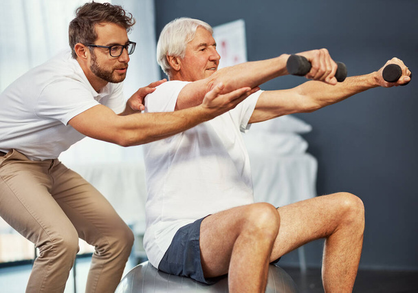 Seis siihen paikkaan. vanhempi mies työskentelee toipumisensa parissa miespuolisen fysioterapeutin kanssa - Valokuva, kuva