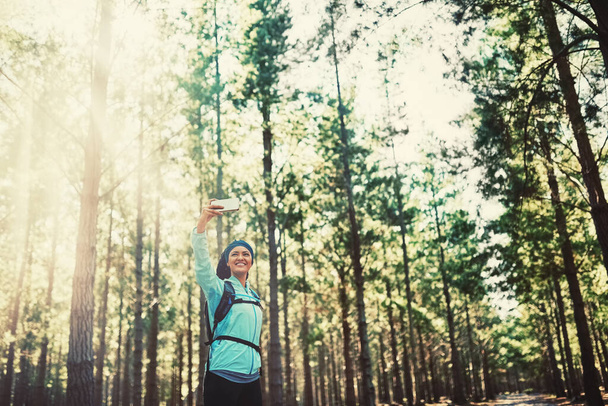 Работаю над собой, для себя. атлетичная молодая женщина делает селфи во время пробежки в лесу - Фото, изображение