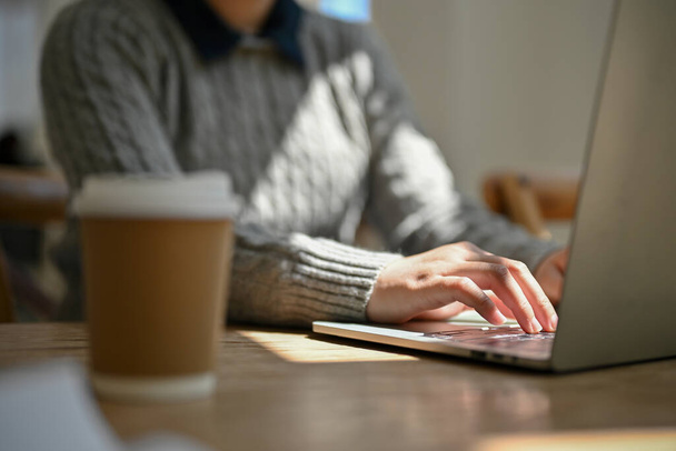 Cropped image of a female using her laptop computer, typing on keyboard, reading online news on the website, managing her work on notebook at the coffee shop. - 写真・画像