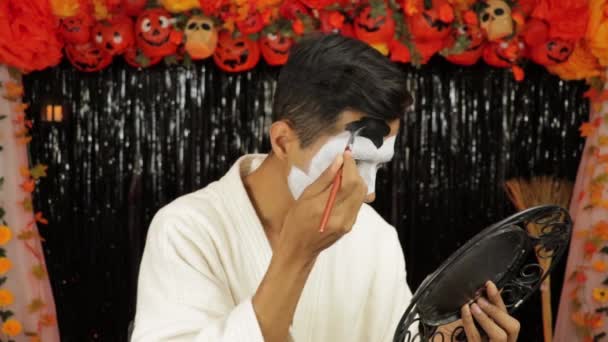 Brown-skinned boy in bathrobe putting on makeup for halloween party. Scary decoration. - Footage, Video