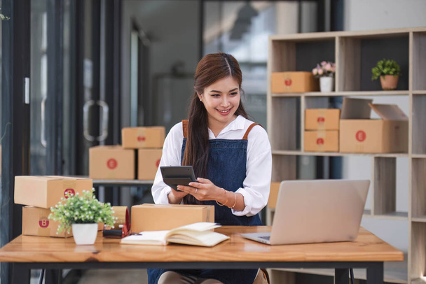 Portrait business woman smile and use tablet checking information on parcel shipping box before send to customer. Entrepreneur small business working at home. SME business online marketing... - Foto, afbeelding