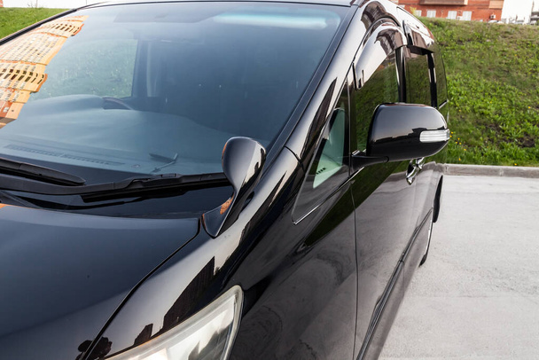 Крупный план бокового левого зеркала и окна кузова автомобиля черный внедорожник на уличной парковке после стирки и детализации в автосервисе. Безопасность дорожного движения
 - Фото, изображение