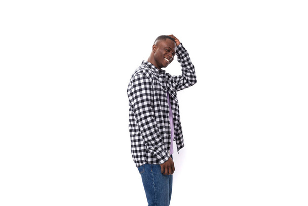30-jähriger Afrikaner in einem karierten schwarz-weißen Hemd posiert auf einem isolierten Hintergrund mit Kopierraum. - Foto, Bild