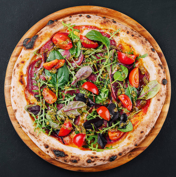 Top view pizza with salami, tomatoes and basil with arugula - Foto, afbeelding