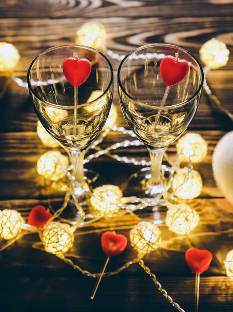 Romantic wine glasses with hearts for Saint Valentine's day. Date and dinner. Cosy lights. Wooden background. Holiday postcard. Love concept. - Φωτογραφία, εικόνα