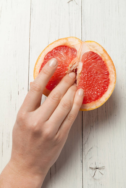 Two female fingers in grapefruit, woman masturbation and sex concept. Vagina and clitoris symbol. - Foto, imagen