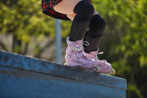 Skater girl grinding on a ledge in a outdoor skatepark in summer. Aggressive inline roller blader female performing a bs royale grind trick - Fotoğraf, Görsel