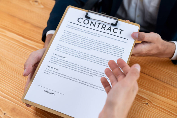 ビジネスマンは企業パートナーシップの契約書を注意深くレビューします。専門的なビジネスの決定のための会議のテーブルの顧客の読書契約の契約および条件。エンティティ - 写真・画像