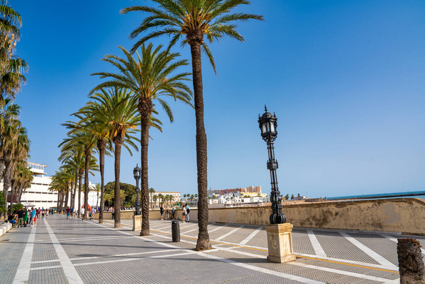 Cadiz, Ισπανία - 8 Απριλίου 2023: Οι τουρίστες στην πόλη περιπάτους κατά μήκος του ωκεανού. - Φωτογραφία, εικόνα