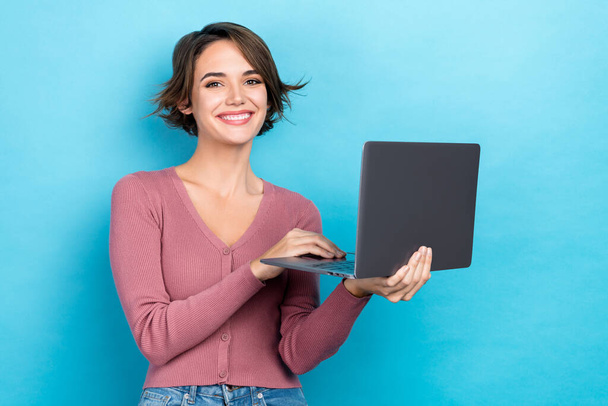 Portrait of nice cute good mood girl with short hairdo wear pink cardigan typing message on laptop isolated on blue color background. - Foto, immagini
