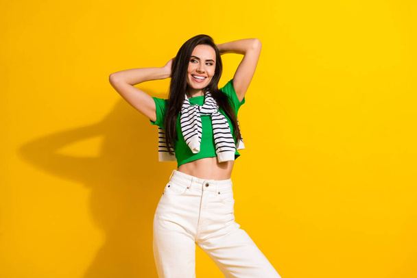 Photo of shiny adorable girl dressed green t-shirt arms behind head looking empty space isolated yellow color background. - Fotografie, Obrázek