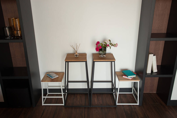 Mesa de madera Shabby con sillas y jarrón situado cerca de cómodo sofá contra paredes de luz con decoraciones en apartamento moderno. Foto de alta calidad - Foto, imagen