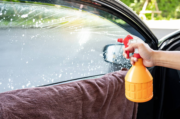 Auto specialist worker hand using foggy spray bottle spraying soapy solution or ammonia fumes for removing old car window film tint. Car side window film removal and tinting installation - Φωτογραφία, εικόνα