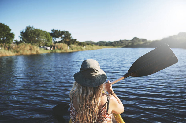 Pagaiare in pace attraverso un ambiente bellissimo. una giovane donna in kayak su un lago - Foto, immagini
