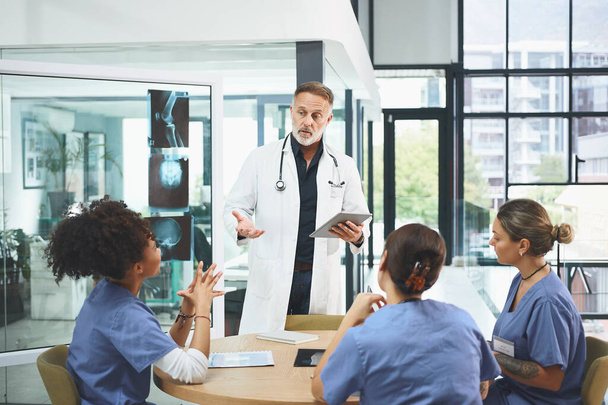 A levar a equipa dele avante com um plano. um médico maduro liderando uma discussão com seus colegas em um hospital - Foto, Imagem