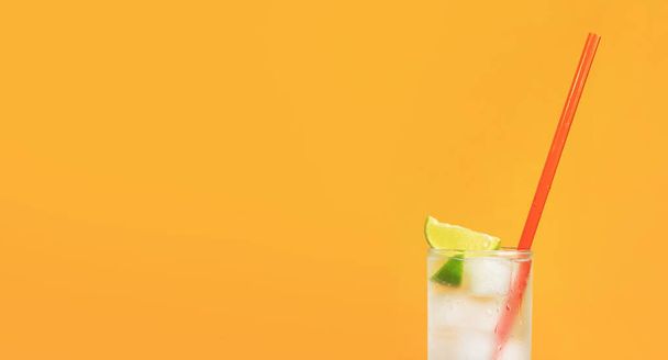 Eistee mit Eis und Limette auf orangefarbenem Hintergrund. Sommercocktail mit Kaltgetränk. Kopierraum - Foto, Bild