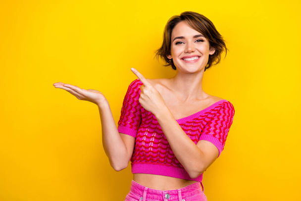 Portrait of lovely cheerful glad lady wear stylish pink clothes presenting empty space opening store isolated on yellow color background. - Foto, Imagen