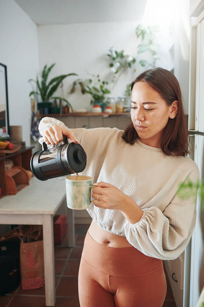 Моя любимая часть дня кофе. молодая женщина наливает себе чашку кофе - Фото, изображение
