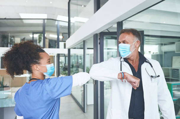 Polulla, joka estää Covidia leviämästä. komea kypsä lääkäri seisoo ja kyynärpää törmäävät hänen sairaanhoitaja tervehdys klinikalla - Valokuva, kuva