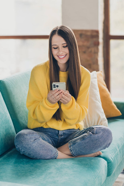 Full size vertical photo of positive peaceful person sit comfy couch use smart phone communicate write blog post flat indoors. - Zdjęcie, obraz