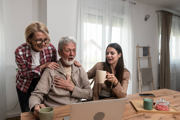 Happy three-generation family hugging sit indoors enjoy time together at home, laughing grown up daughter with 70s dad and middle-aged 50s mom warm relations, intergenerational relative people concept - Foto, afbeelding