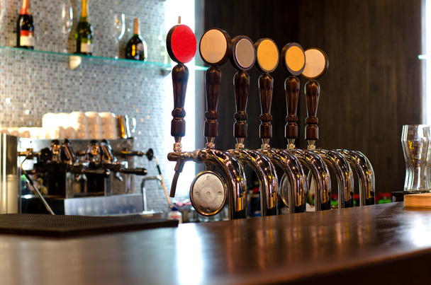 Grifos de cerveza detrás de un mostrador de bar
 - Foto, imagen