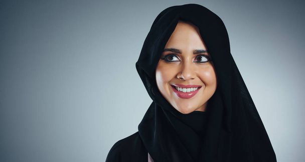 Es fällt schwer, nicht zu lächeln, wenn man ihr Lächeln sieht. Studioaufnahme einer jungen muslimischen Geschäftsfrau vor grauem Hintergrund - Foto, Bild