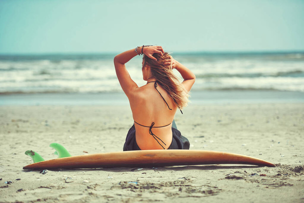 The best thing to do on a summers day. a beautiful young woman going for a surf at the beach - Zdjęcie, obraz