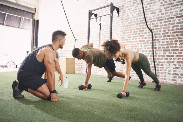Having a fitness instructor is always a good idea. two people working out with a fitness instructor at the gym - Foto, imagen
