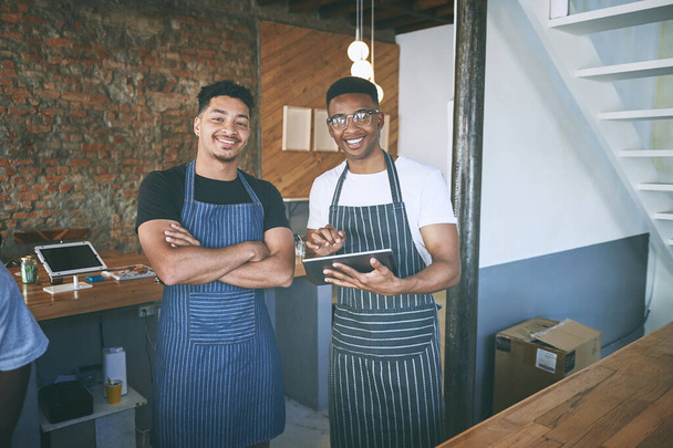 Het beste van het beste in de koffie business. twee jonge mannen die een digitale tablet gebruiken terwijl ze in een café werken - Foto, afbeelding