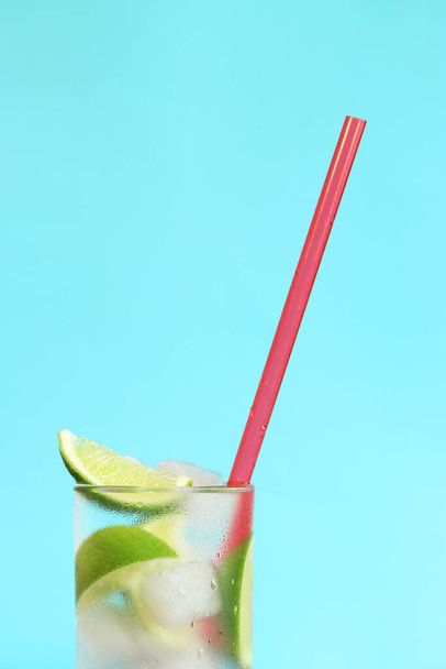 Limonade mit Eis und Limette auf hellblauem Hintergrund. Sommercocktail mit Kaltgetränk. Kopierraum. Trinken mit einem Strohhalm in Großaufnahme - Foto, Bild