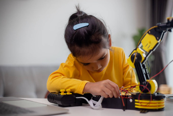 STEM-onderwijsconcept. Aziatische studenten leren thuis door het coderen van robotarmen in STEM, wiskundetechniek technologie computercode in robotica voor kinderconcepten. - Foto, afbeelding